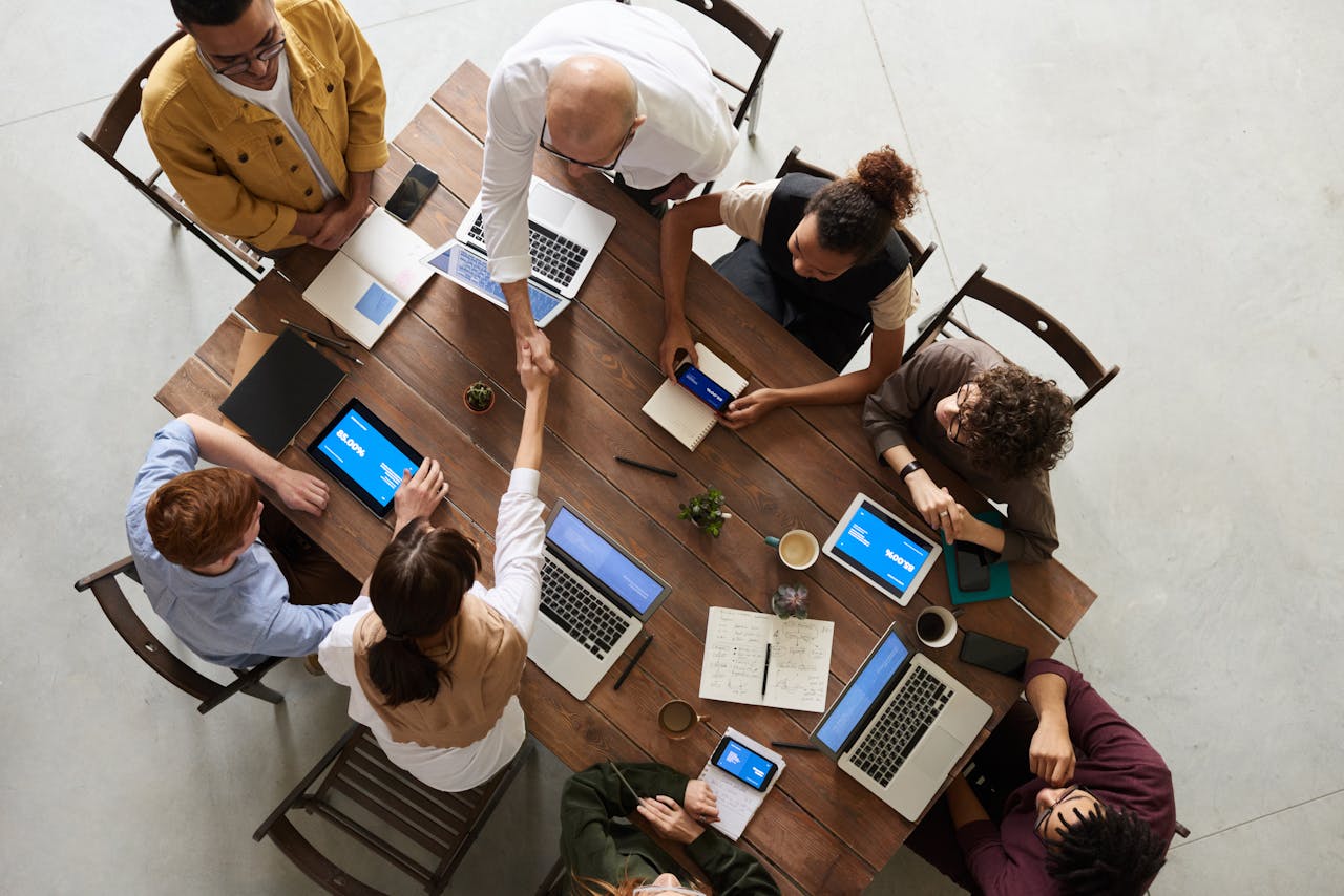 Services-01 Top view of a diverse team collaborating in an office setting with laptops and tablets, promoting cooperation.
